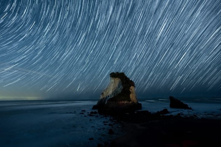 夜幕下的海上孤礁仰望放射状星轨，以及多颗飞跃天际的流星 | Photo © Philo Li